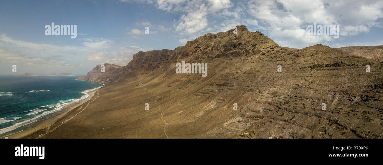 Vue aérienne de la plage de Famara, Lanzarote, îles Canaries, Espagne. Di Risco de Famara, relief, montagne surplombant l'océan Atlantique. Chemin de terre Banque D'Images