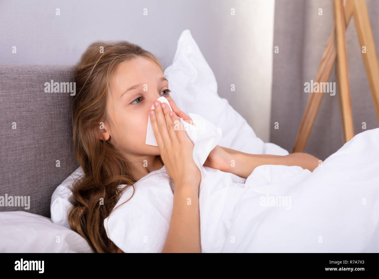 Jeune fille souffrant de soufflage froid son nez avec un mouchoir sur le lit Banque D'Images