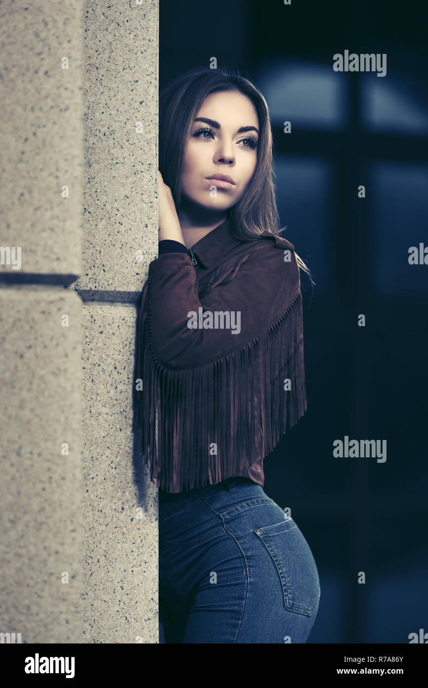 Triste Jeune femme debout sur le mur en face de la ville de mode élégant cuir daim frange modèle jacket Banque D'Images