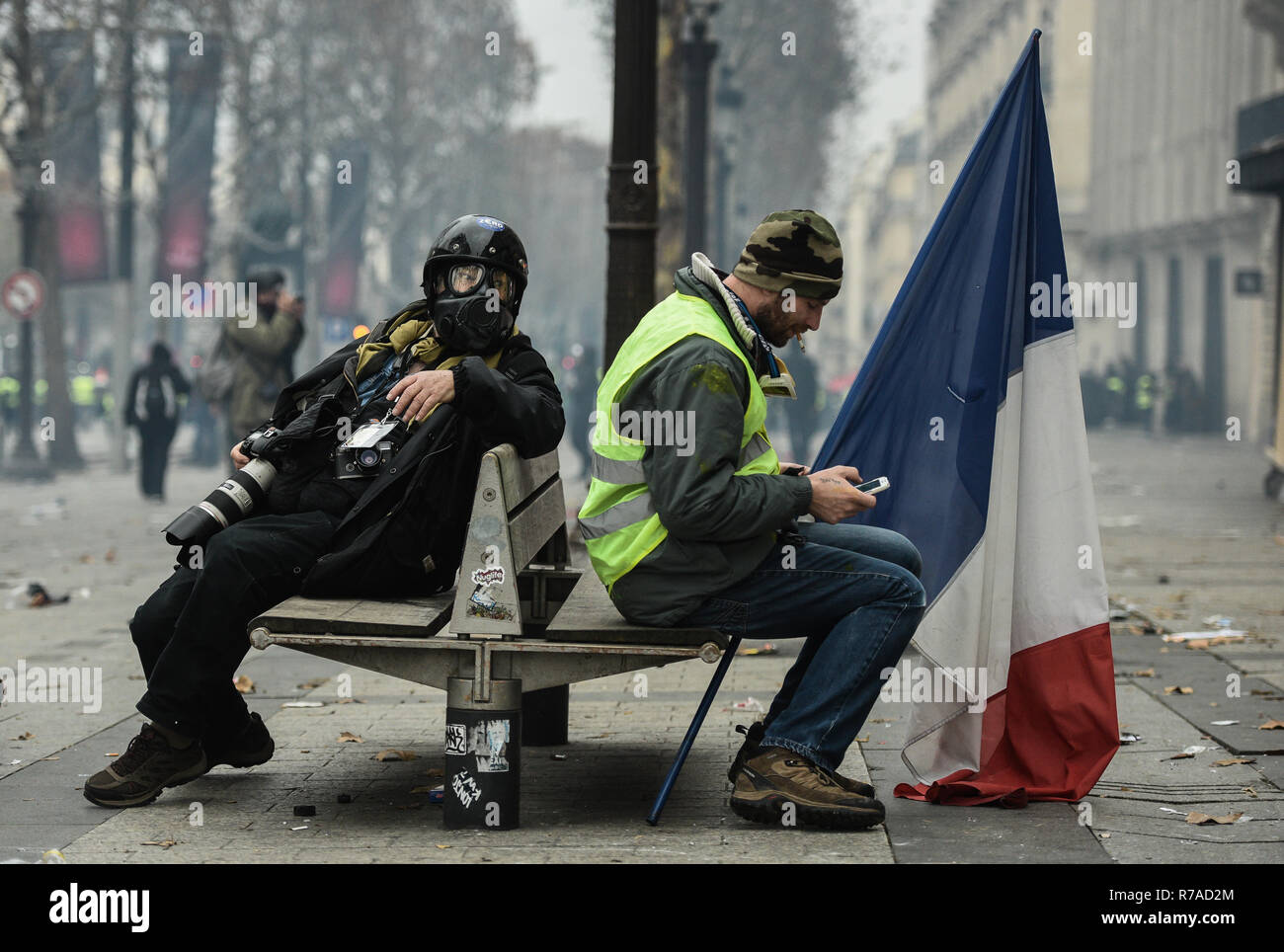 Paris, France. 8 décembre 2018. Photographe portant un masque de gaz  lacrymogène est assis à côté d'un jaune (gilets jaunes) manifestants lors  de démos contre le coût de la vie et l'augmentation