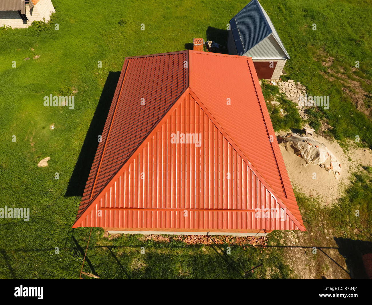 Maison avec un toit orange en métal, vue d'en haut. Profil métallique ondulé peint sur le toit. Banque D'Images