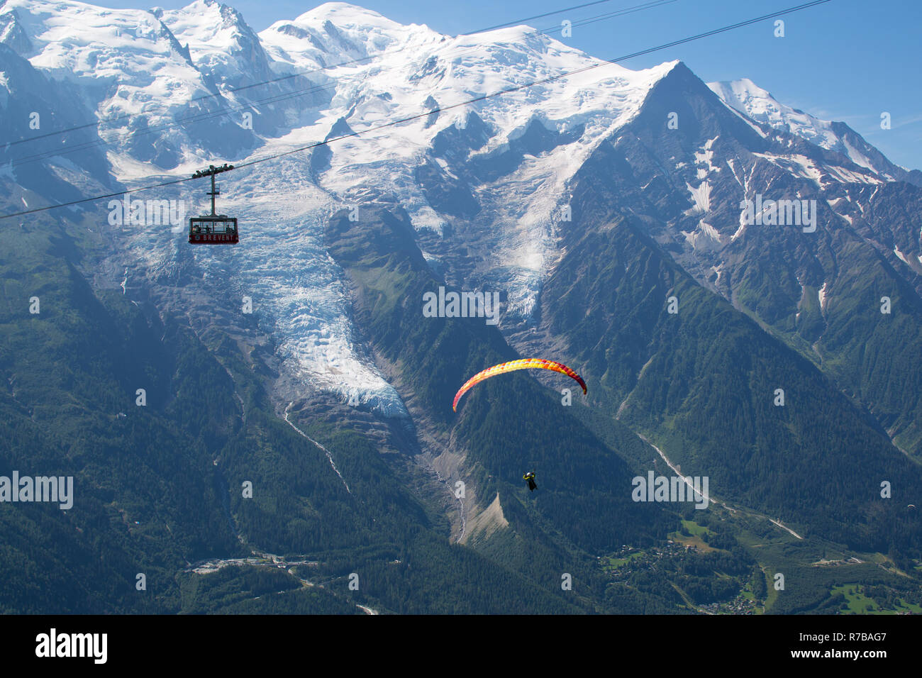 Un parapente pilote aux commandes et le téléphérique du Brévent en passant en face du Mont Blanc et le glacier des Bossons, au-dessus de Chamonix. Banque D'Images