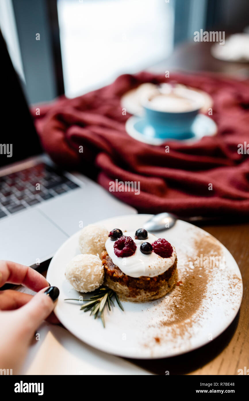 Vue de dessus de designers. Womens part garder la cuillère. Offres d'espace de travail. Ordinateur portable avec téléphone mobile, tasse de café et dessert sur la table en bois. Banque D'Images