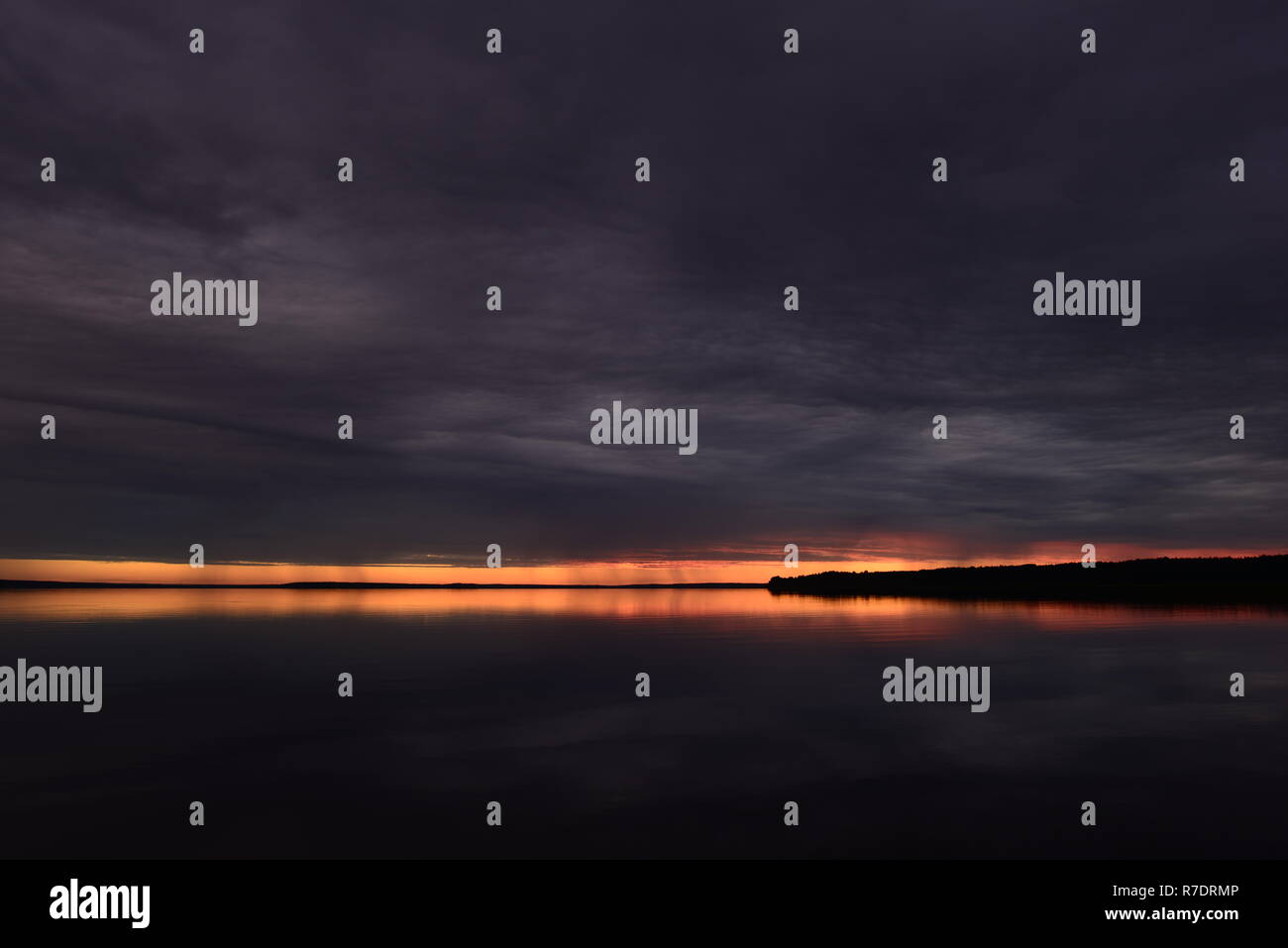 La tombée de la lumière résiduelle de la lumière du soleil au coucher du soleil avant la nuit dans le ciel sombre sur la surface de l'eau du lac Banque D'Images