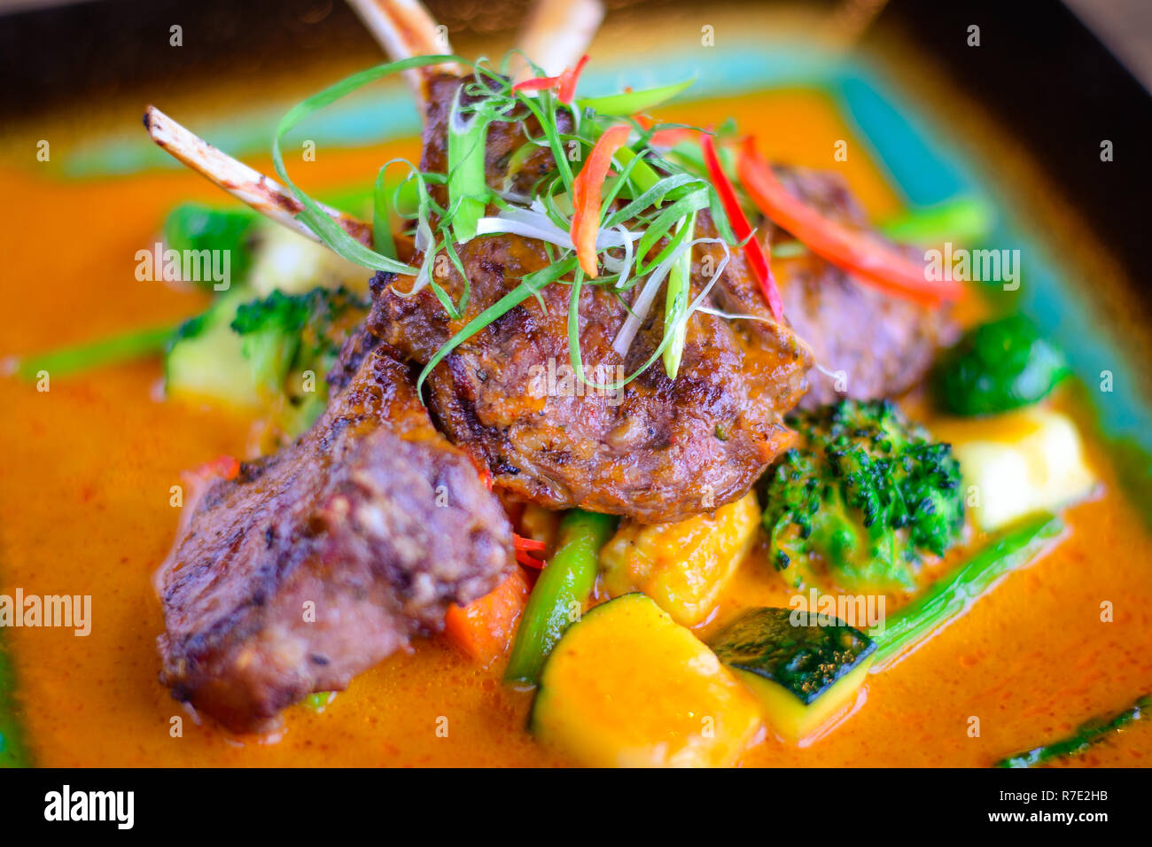 Jarret d'agneau grillé avec légumes grillés sur un lit de curry doux Banque D'Images