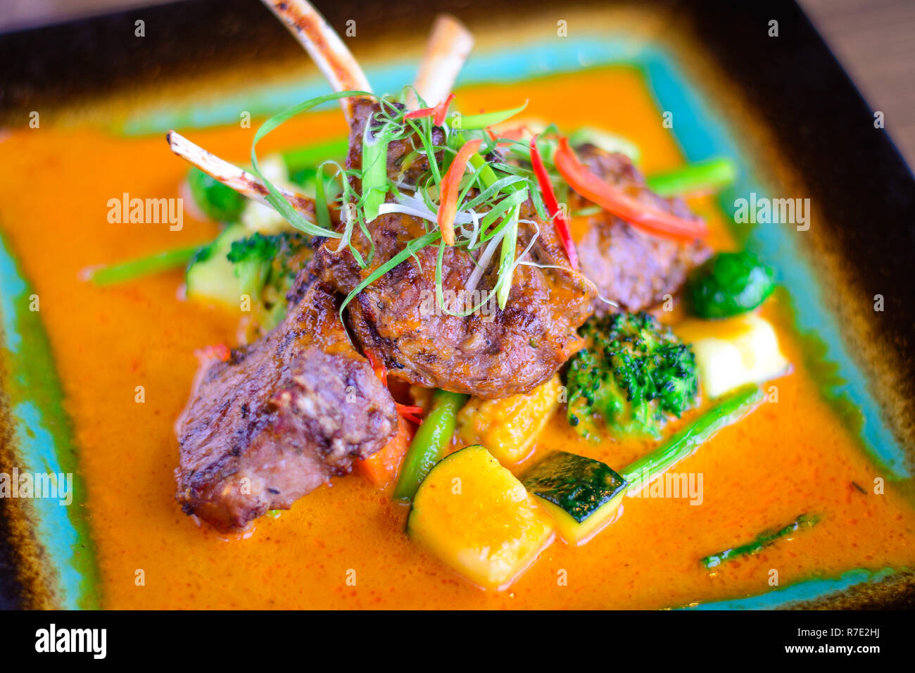 Jarret d'agneau grillé avec légumes grillés sur un lit de curry doux Banque D'Images