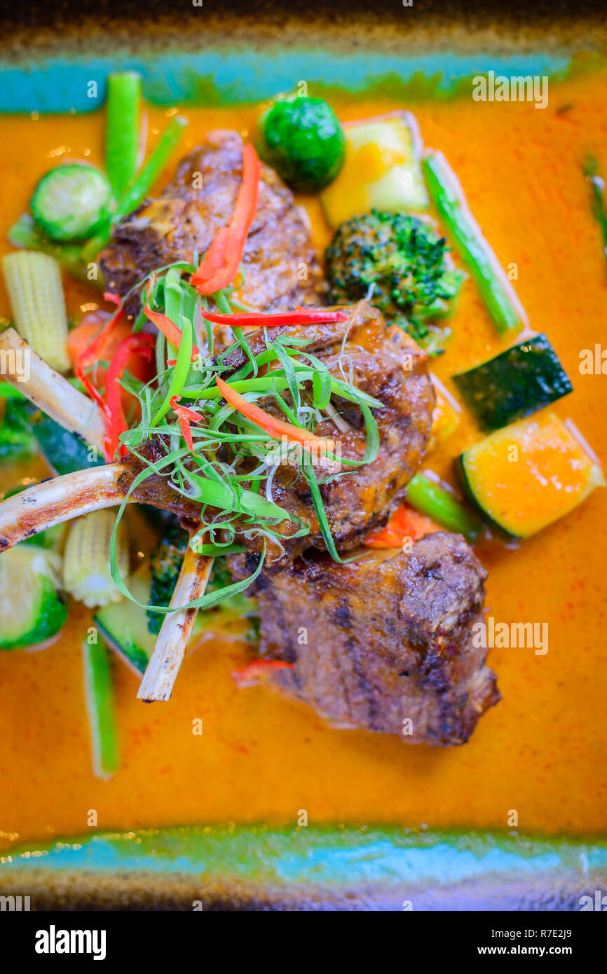 Jarret d'agneau grillé avec légumes grillés sur un lit de curry doux Banque D'Images