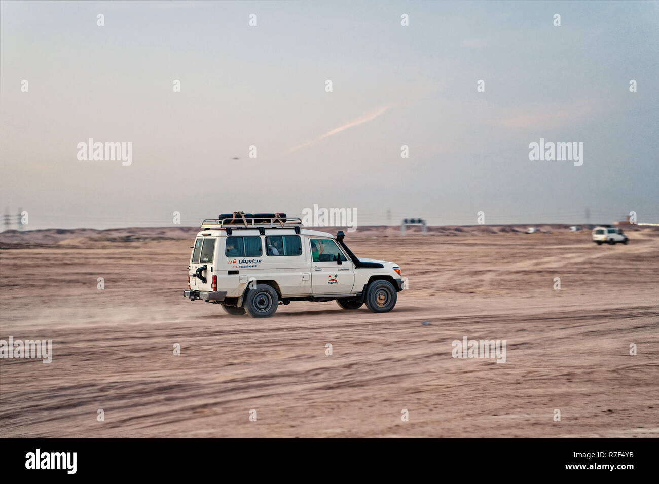 Hurghada, Egypte - 26 Février 2017 : safari dans le désert. Véhicule hors route, voiture blanche ou jeep la conduite dans les dunes de sable sur fond de ciel gris. L'activité extrême. La découverte et l'aventure. Locations et wanderlust Banque D'Images