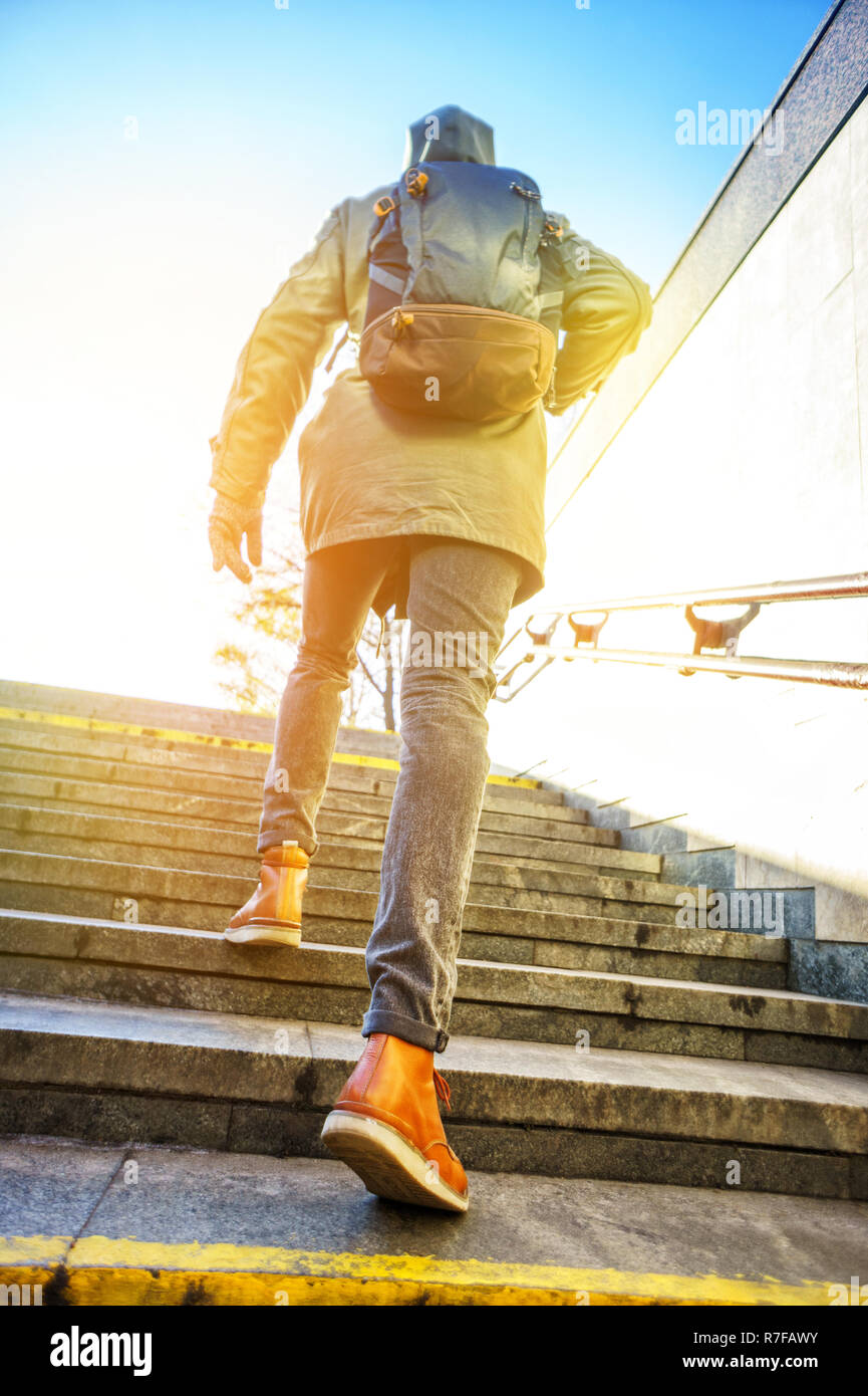 L'homme tourisme dans une hotte avec un grand sac à dos, monte les  escaliers à l'aube dans un environnement urbain. En hiver tourisme concept  ville Photo Stock - Alamy