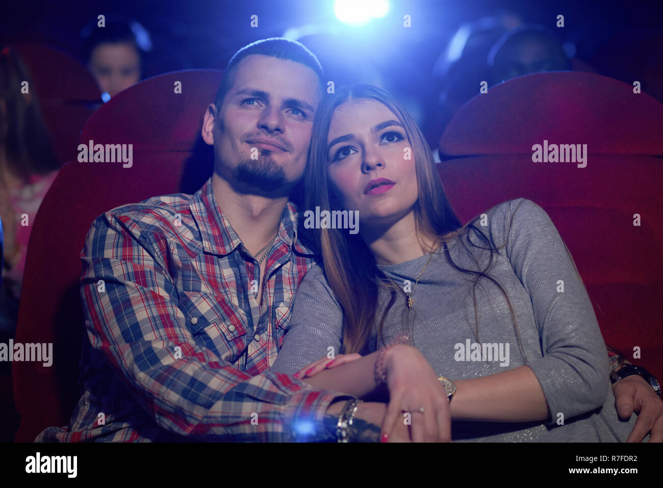 Vue avant du couple dans le cinéma, regarder la comédie ou film romantique. Beau barbu hugging belle amie assis près de film alors que l'examen. Concept de loisirs. Banque D'Images