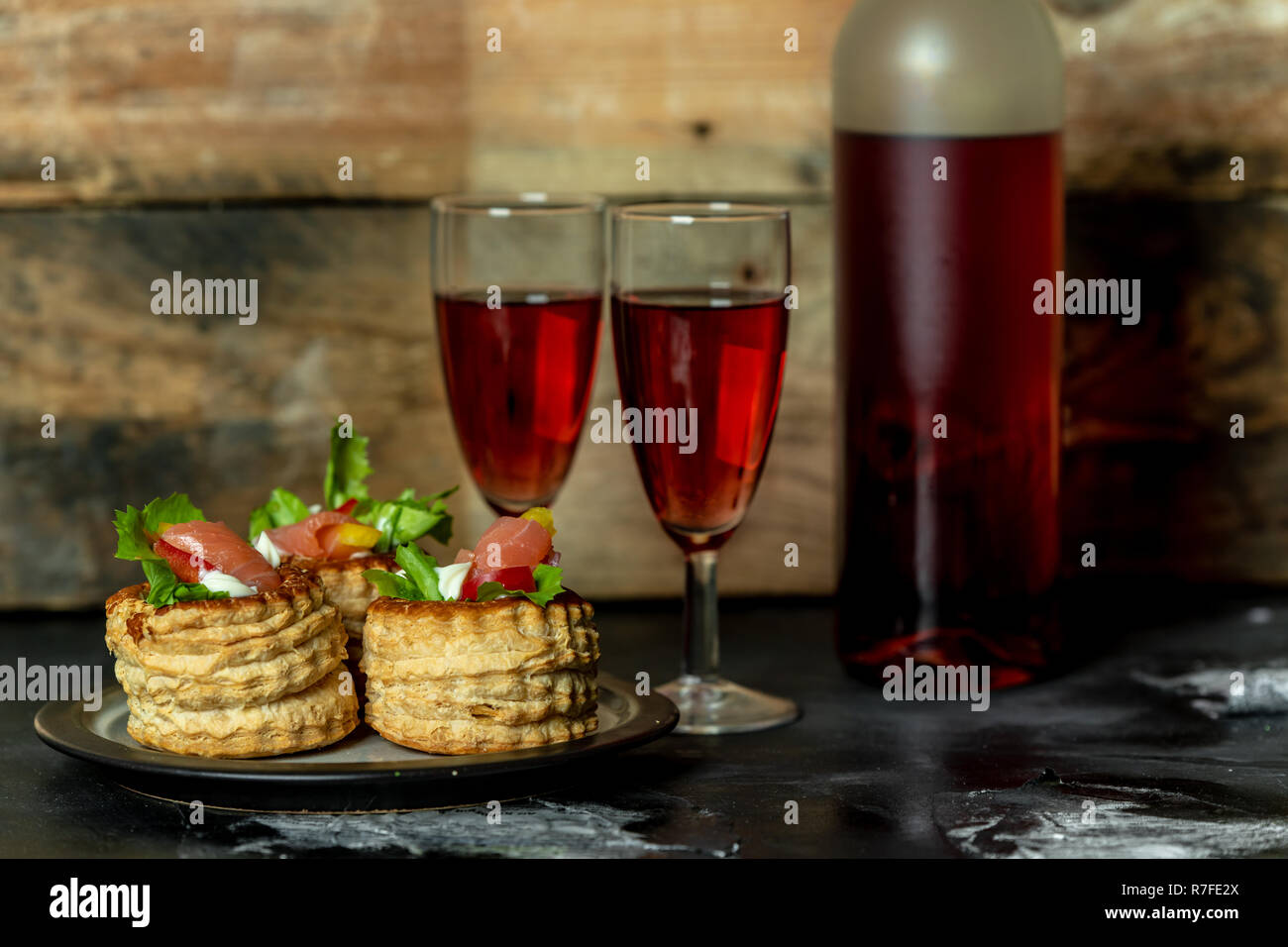 La cuisine française, les Galettes croquantes de laitue et de saumon fumé sur un fond en bois, rustique, à côté d'un verre de vin rouge Banque D'Images