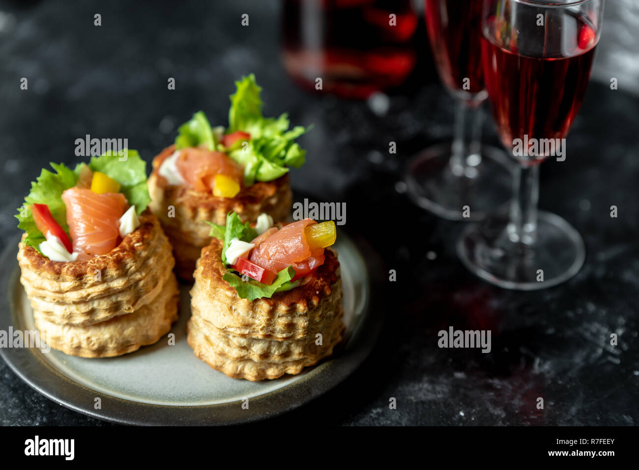 La cuisine française, les Galettes croquantes de laitue et de saumon fumé sur un fond sombre, rustique, à côté d'un verre de vin rouge Banque D'Images