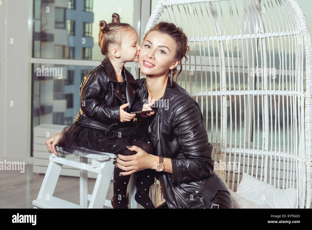 Portrait d'une jeune mère et sa fille. Girl kisses maman sur les joues. Banque D'Images