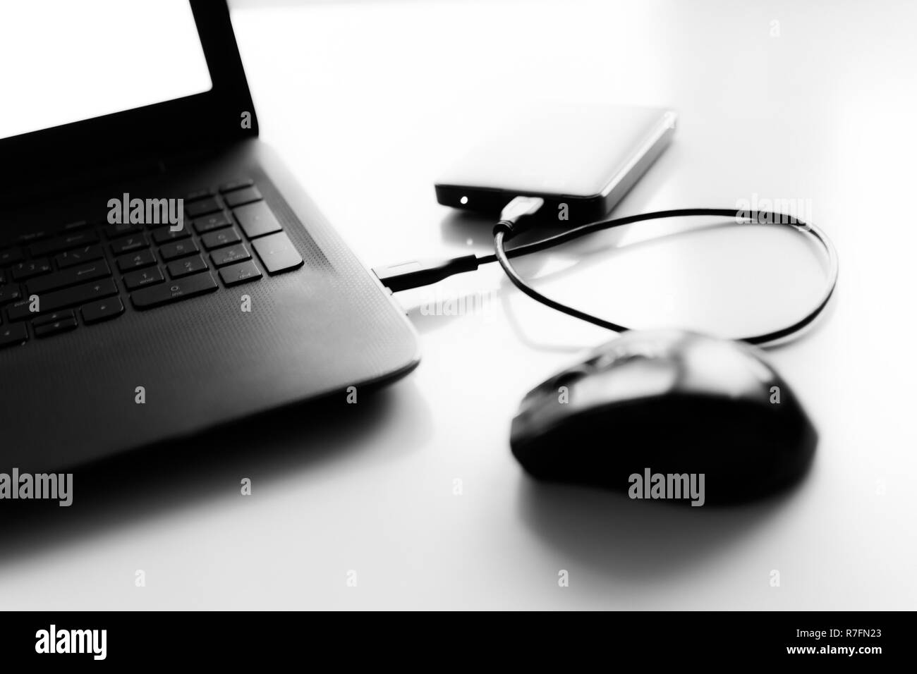 Disque dur pour ordinateur portable noir et blanc de la souris sur le bureau est floue. Banque D'Images