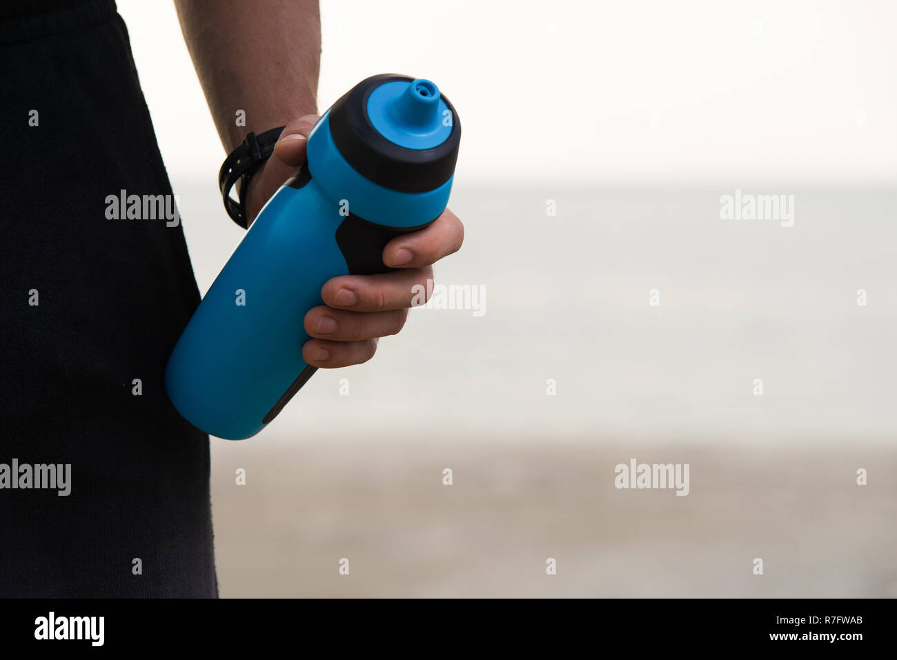 Close-up de remise en forme de shaker en plastique dans la main des hommes. Sportsman toujours en prenant l'eau avec lui. Homme méconnaissable menant un mode de vie sain. Refreshm Banque D'Images