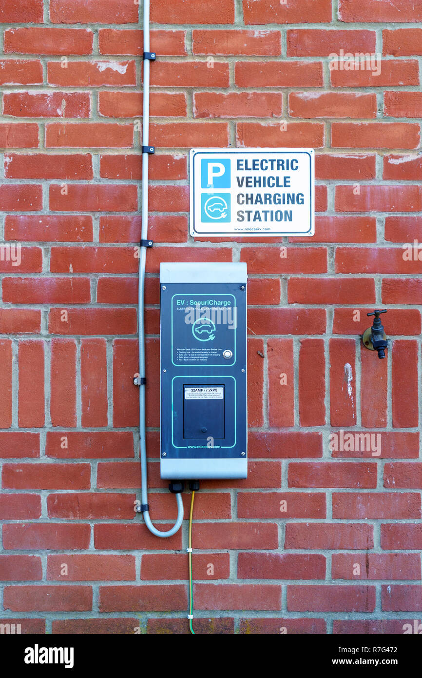 La station de recharge de véhicules électriques sur le mur de brique rouge Banque D'Images