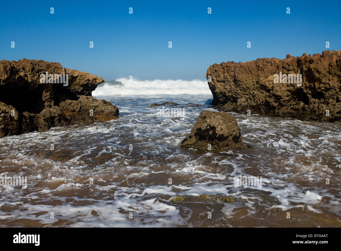 Plage avec peu de rochers sur la côte. L'eau sauvage de l'océan Atlantique avec des vagues. Ciel bleu clair. Horizon dans l'arrière-plan. Plage Beddouza, Maroc. Banque D'Images