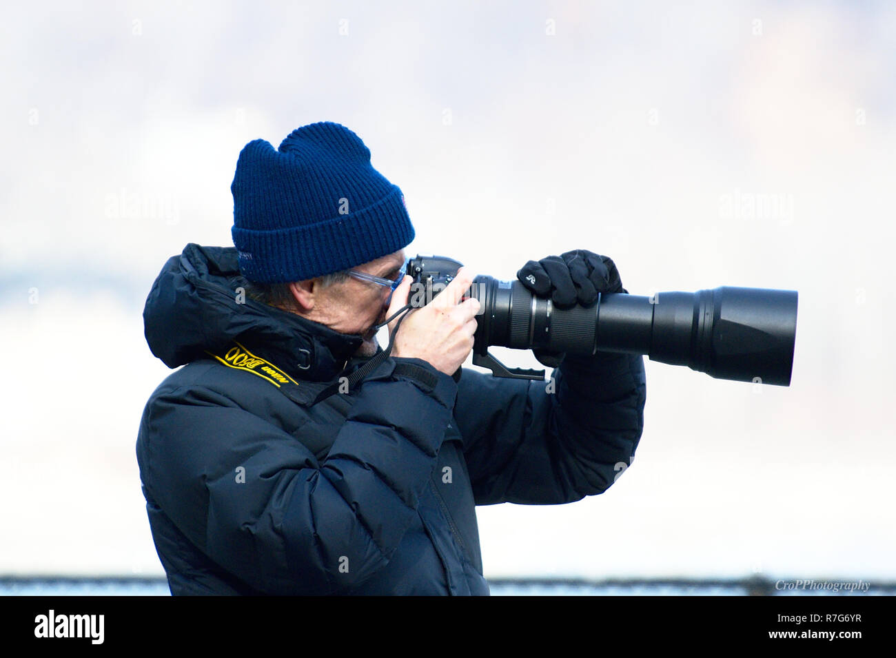Photographe en pointant l'hiver avec de gros appareil photo avec objectif zoom arrière-plan délavé Banque D'Images