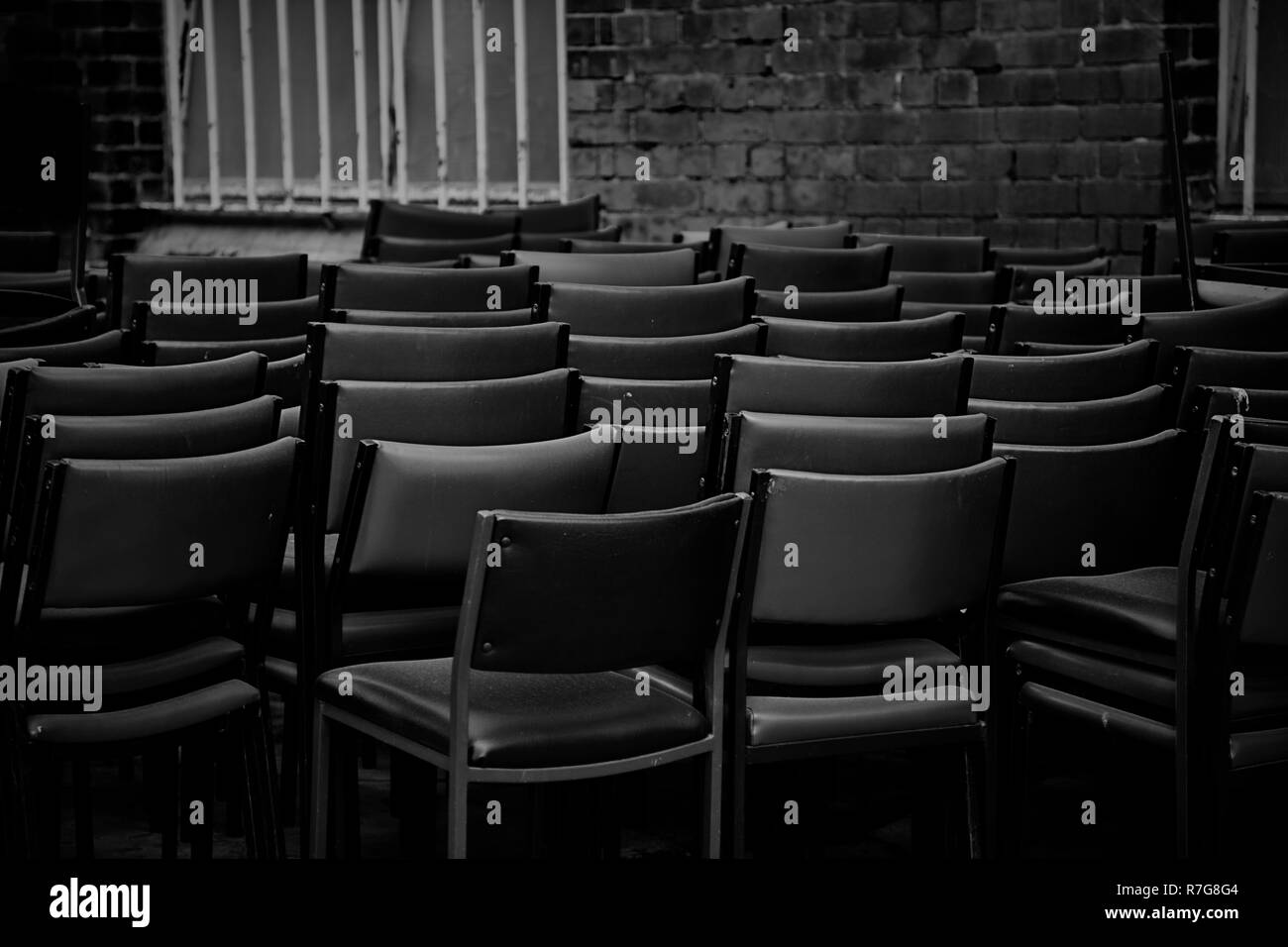 Chaises empilées dans une ruelle sombre pour le stockage. Banque D'Images