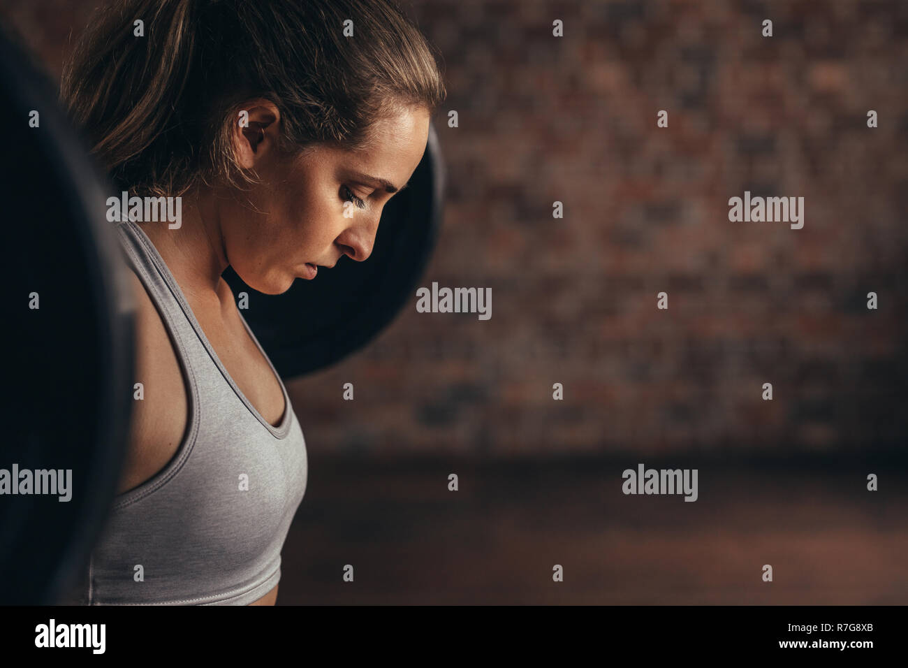 Femme déterminée à gym l'entraînement avec des poids lourds. Mettre en place les jeunes filles l'élaboration avec des poids à l'entraînement en salle de sport. Banque D'Images