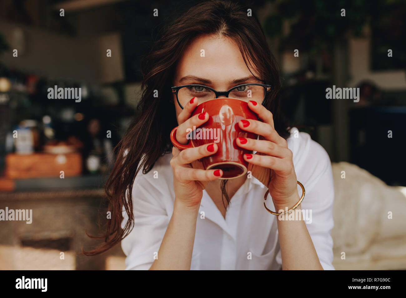 Close up portrait of young woman drinking coffee at cafe. Femme avec des lunettes ayant une tasse de café. Banque D'Images