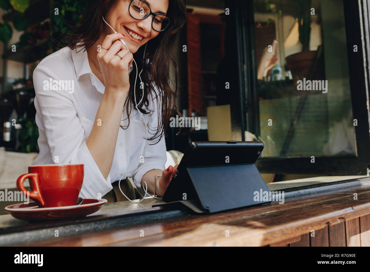 femme d'affaires travaillant à partir d'un café et faisant un appel vidéo avec tablette numérique. Femme freelance au café faisant un appel vidéo. Banque D'Images