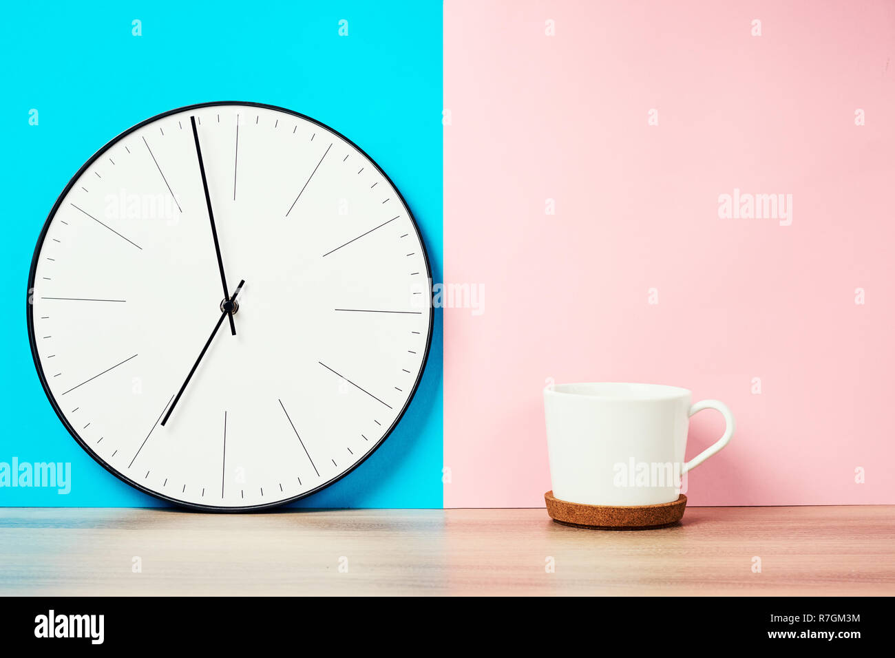 Horloge murale vintage et tasse de café sur fond rose et bleu pastel Banque D'Images