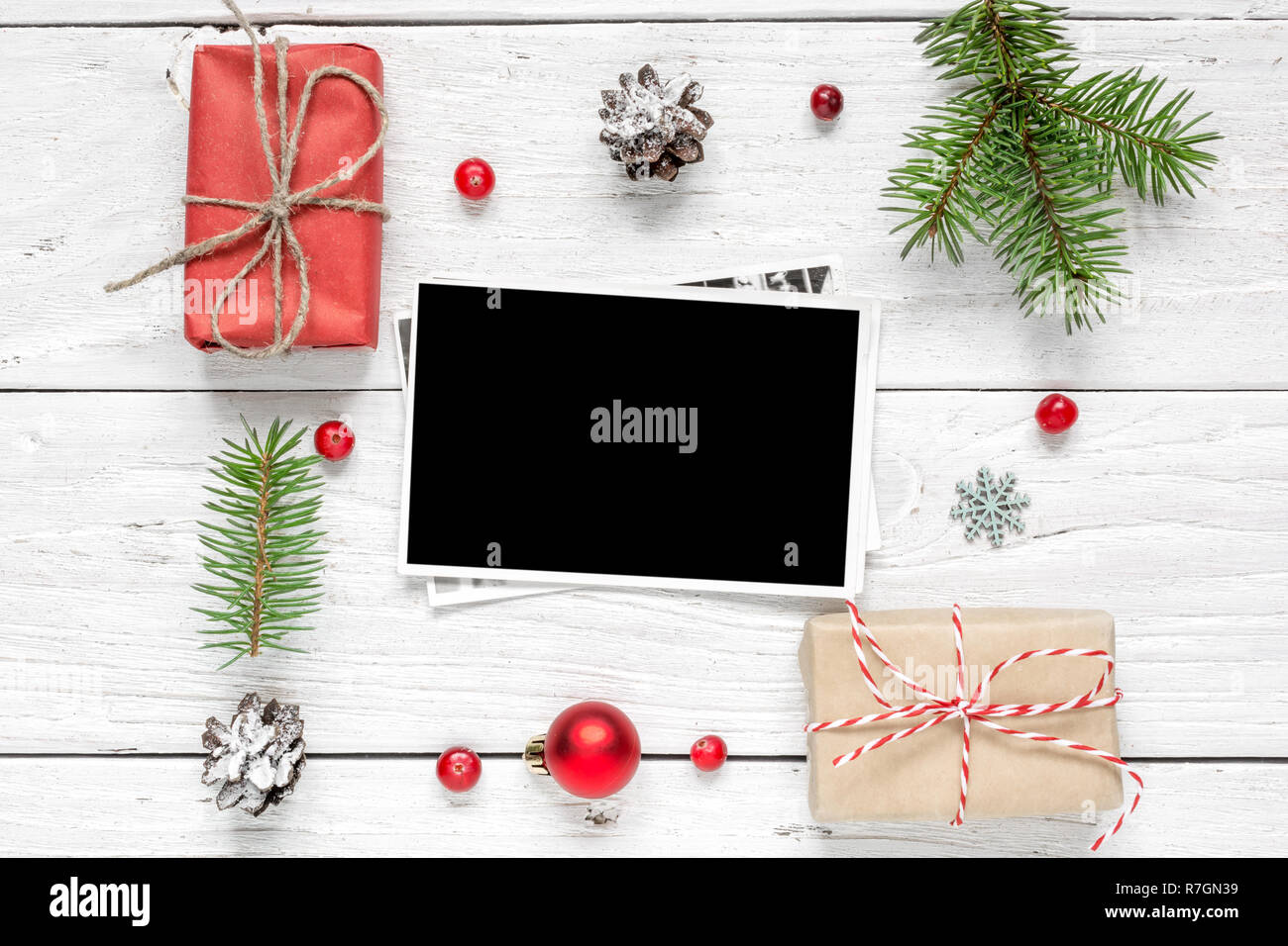 Carte photo vierge dans cadre fait de branches de sapins, décorations et coffrets cadeaux over white background. fond de noël. des maquettes. Télévision. Banque D'Images