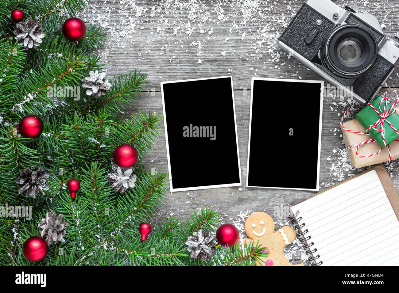 Appareil photo rétro et cadres photo vierge de Noël avec des branches de sapins, décorations, coffrets cadeaux et bordée sur portable fond rustique en bois. Simulation d'u Banque D'Images