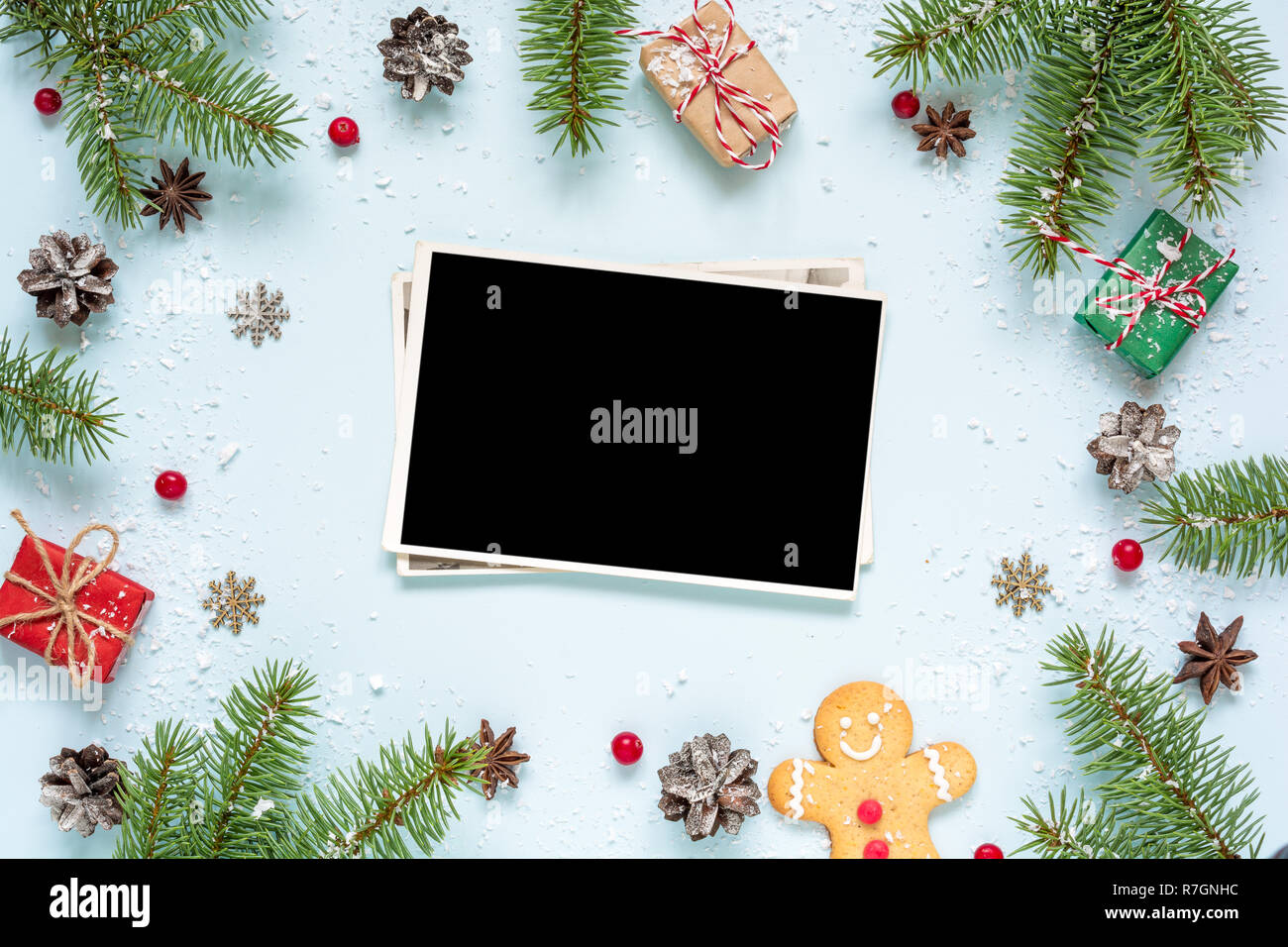 Carte photo vierge noël dans cadre fait de branches de sapins, décorations et coffrets cadeaux sur fond bleu. maquette. Télévision. Vue de dessus Banque D'Images