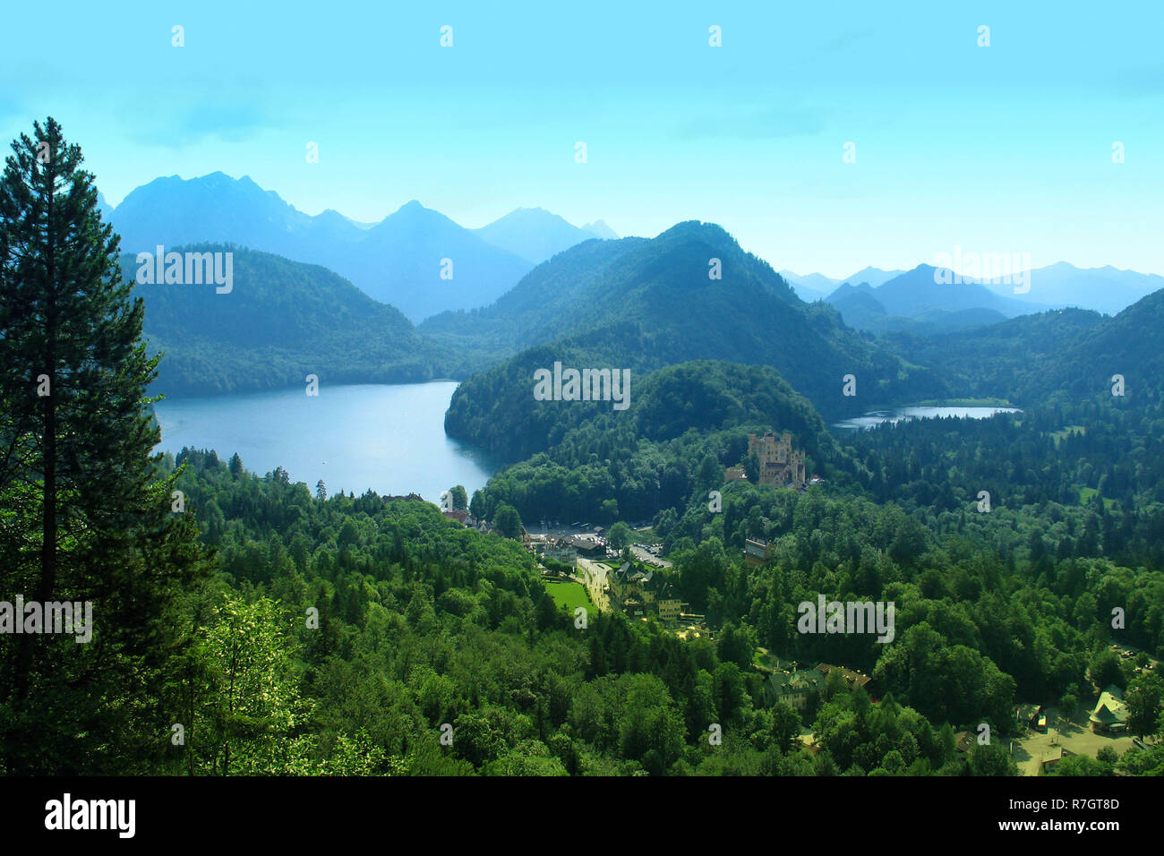 Paysage alpin avec montagnes dans une brume bleue, tranquille lac mirror et vieux château à une distance Banque D'Images