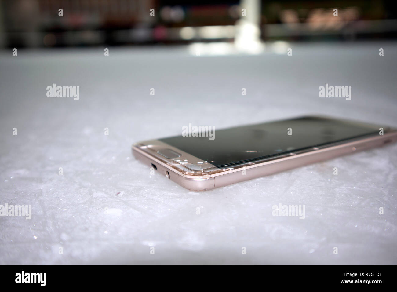 Smart phone moderne avec écran brisé gisant sur la glace en verre rayé Banque D'Images