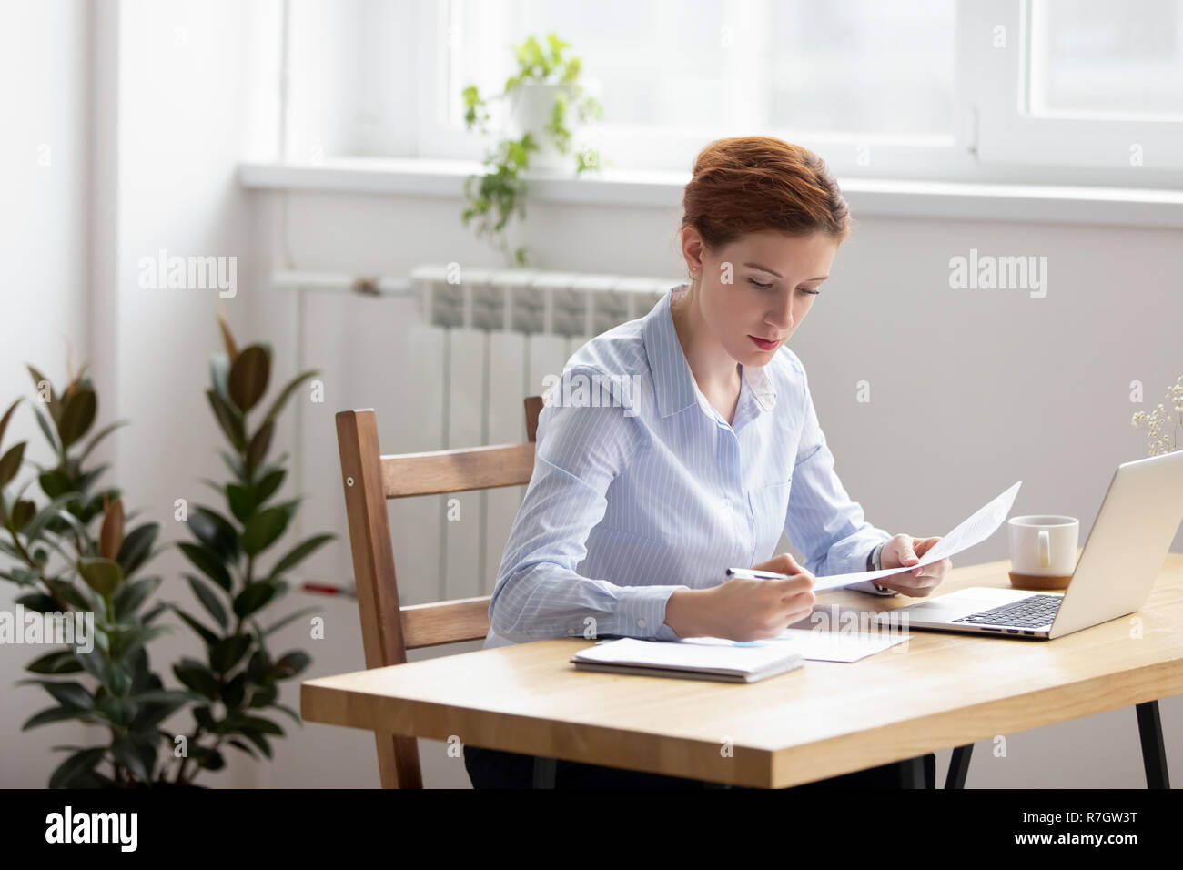 L'accent woman sitting at desk groupe de contrôle des données dans les documents Banque D'Images