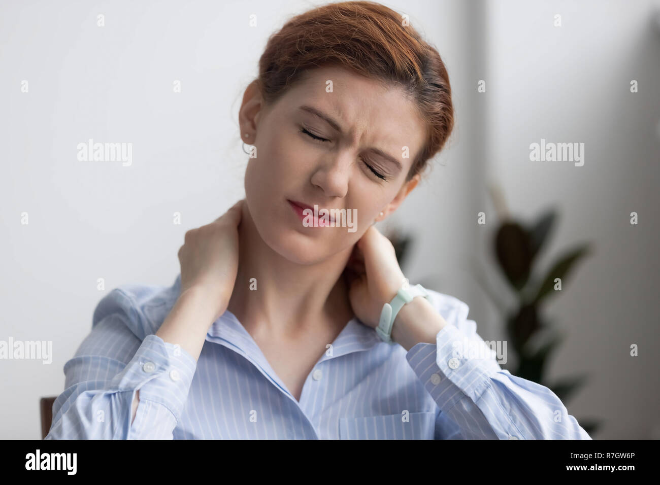 Femme souffre d'une douleur au cou tout en travaillant au bureau Banque D'Images