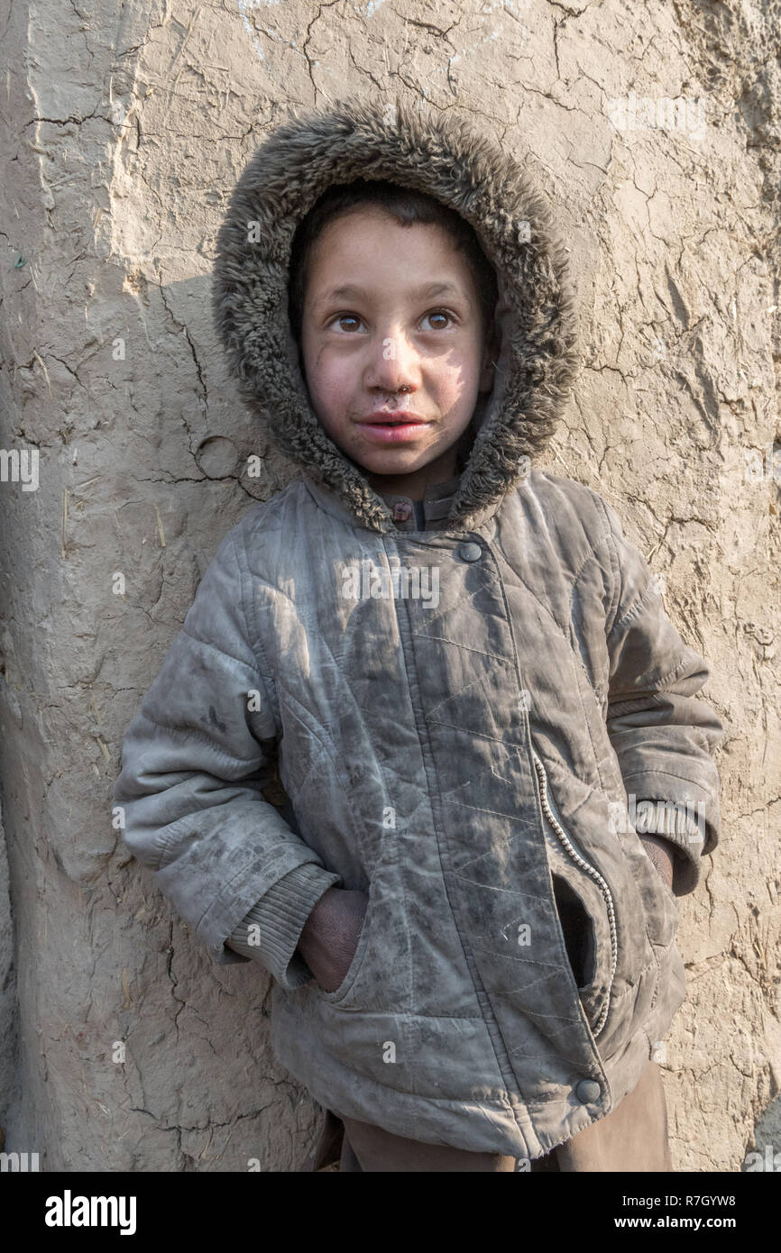 Garçon dont la famille a été déplacée de la province de Helmand en raison des talibans. Il vit dans des conditions difficiles dans un camp de réfugiés près de Kaboul, Afghanistan. Banque D'Images