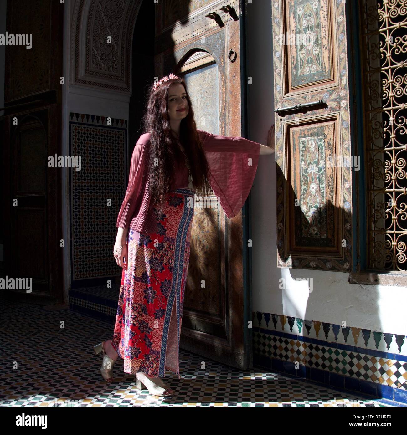 Une dame hippie avec de larges manches rose pose par une porte au Maroc Banque D'Images