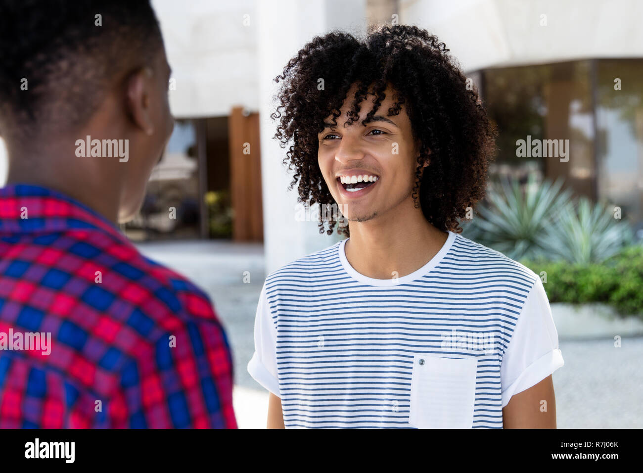 Jeune adulte homme avec de longs cheveux de parler avec une amie de l'Afrique dans la ville Banque D'Images
