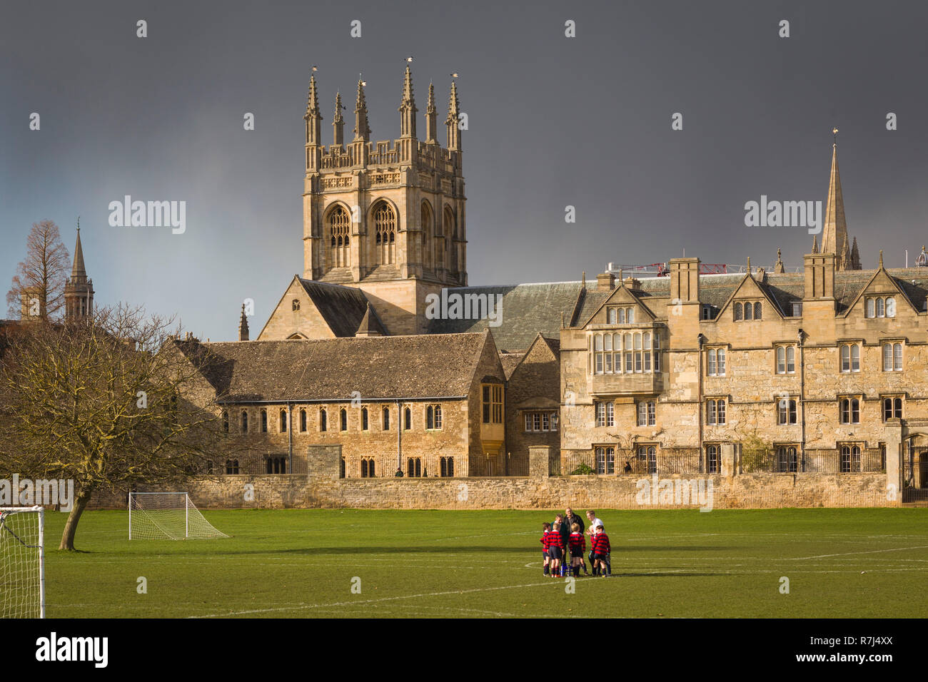 La pratique des écoliers d'Oxford au football sur le terrain de jeux avec Merton Merton College derrière et sombres nuages de tempête Banque D'Images