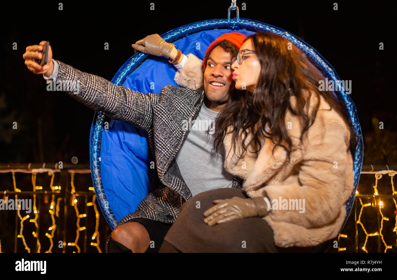 Couple assis sur chaise et prenant à selfies Marché de Noël, Zagreb, Croatie. Banque D'Images