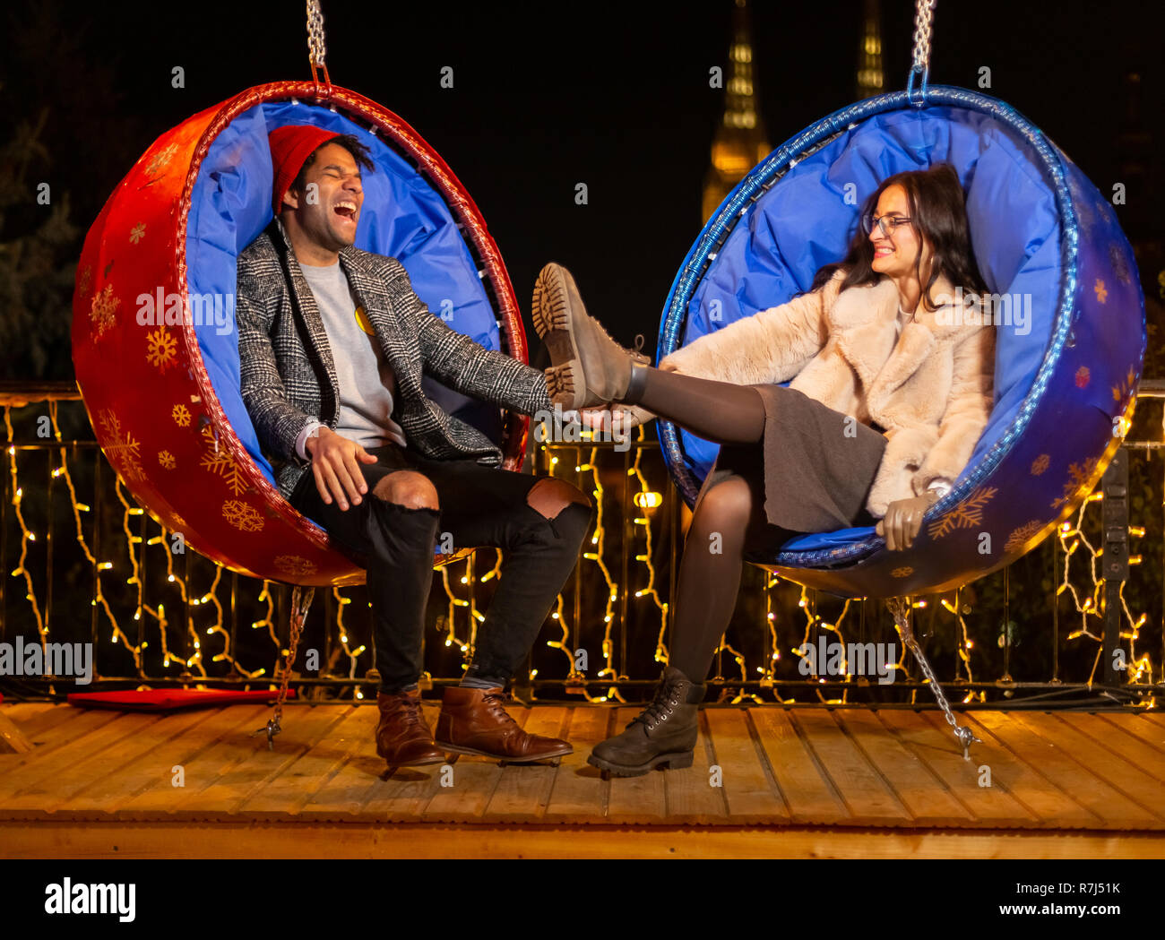 Couple assis sur balançoire et riant de marché de Noël, Zagreb, Croatie. Banque D'Images