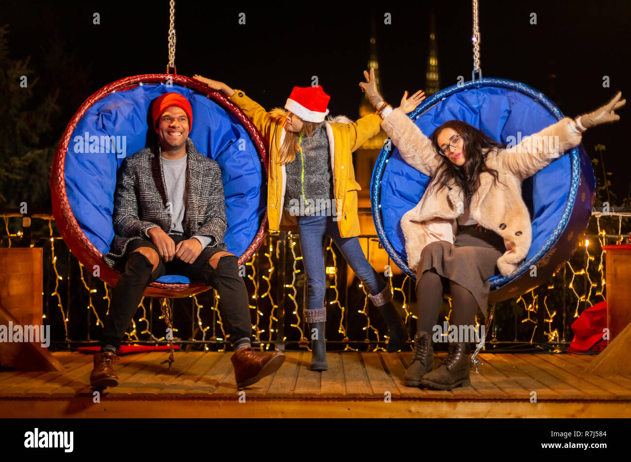 Couple et sa fille s'amusant sur la pendaison chaises Noël, Zagreb, Croatie. Banque D'Images