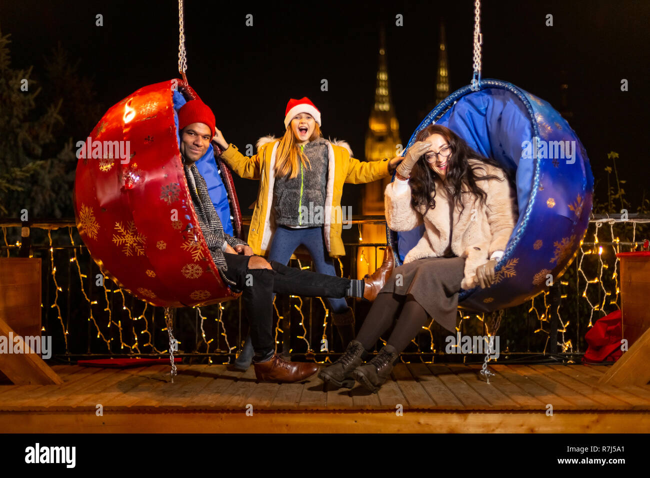 Couple et sa fille s'amusant sur la pendaison chaises Noël, Zagreb, Croatie. Banque D'Images
