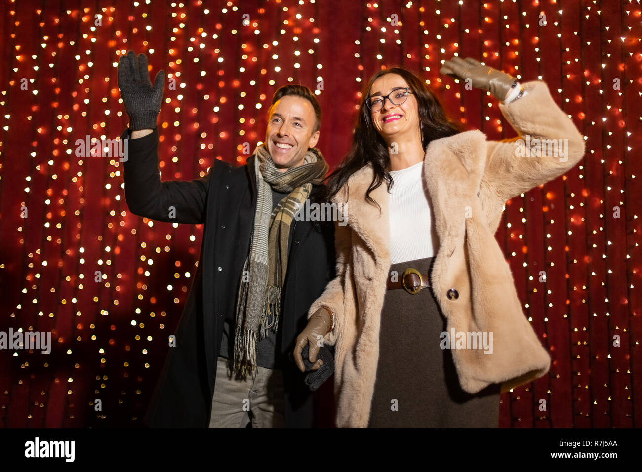 Couple forme pour la photo en face de lumière mur à Marché de Noël. Banque D'Images