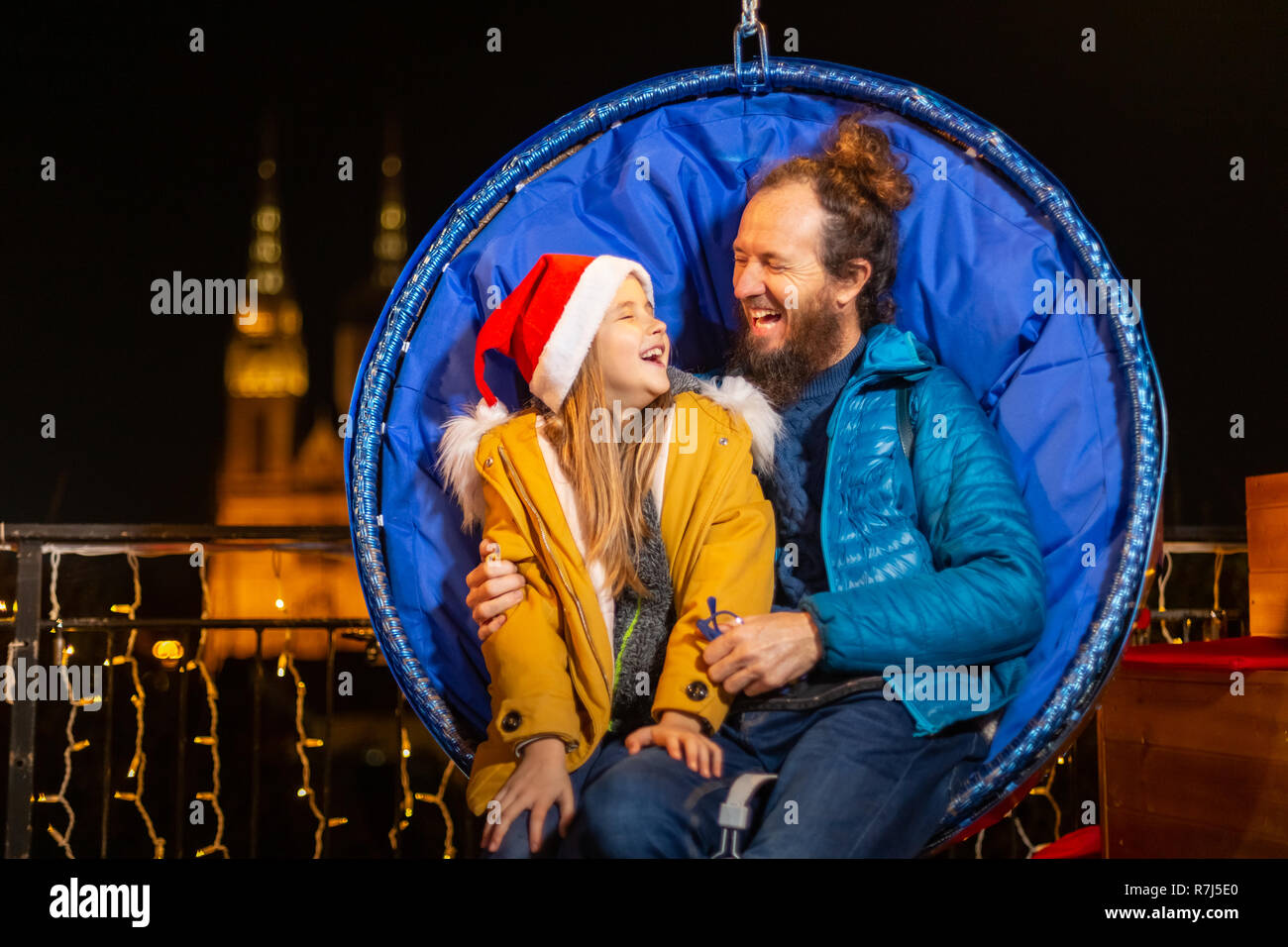 Père et fille assis sur des chaises de Noël suspendus, Zagreb, Croatie. Banque D'Images