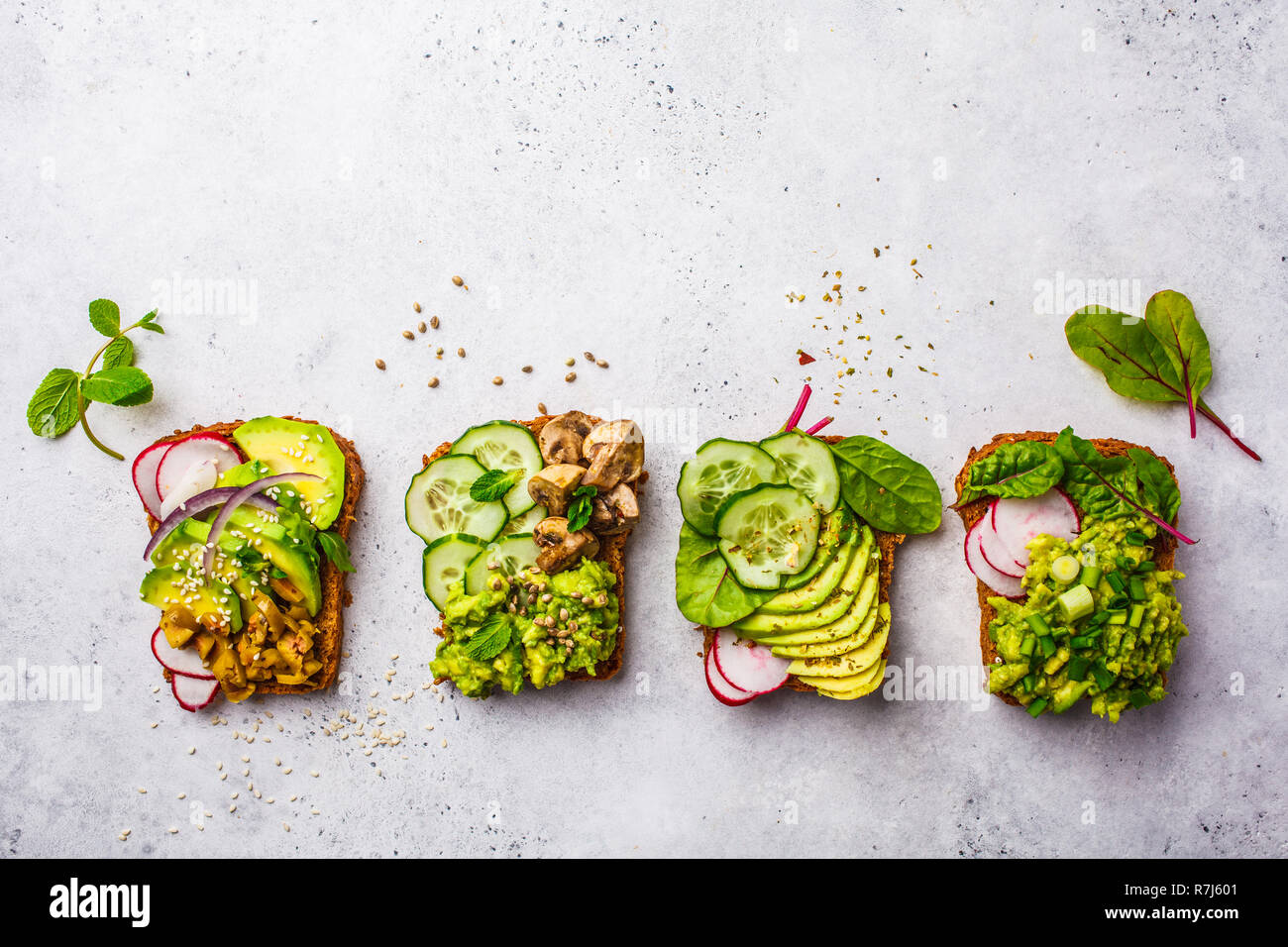 Toasts à l'avocat avec différentes garnitures, du haut de la vue, fond blanc. Régime alimentaire à base de plantes concept. Banque D'Images