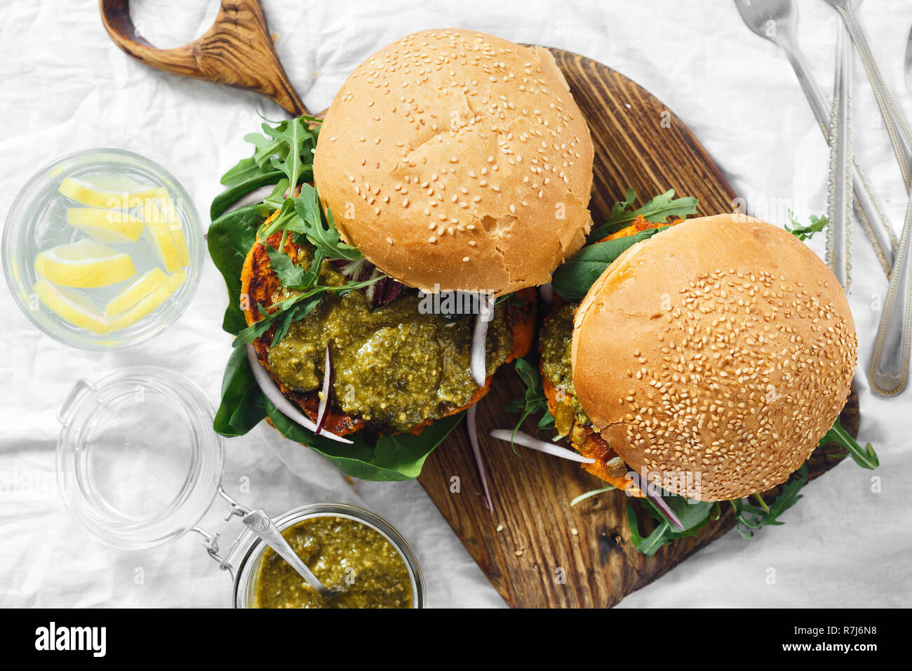 Burger végétarien fait de l'escalope de citrouille, Épinards, roquette et sauce pesto servi sur une planche en bois Vue de dessus. Concept de l'alimentation végétarienne saine Banque D'Images