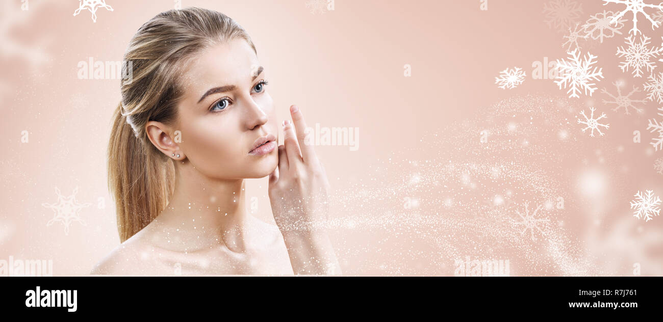 Jeune femme sensuelle sur fond beige avec des flocons de neige. Banque D'Images