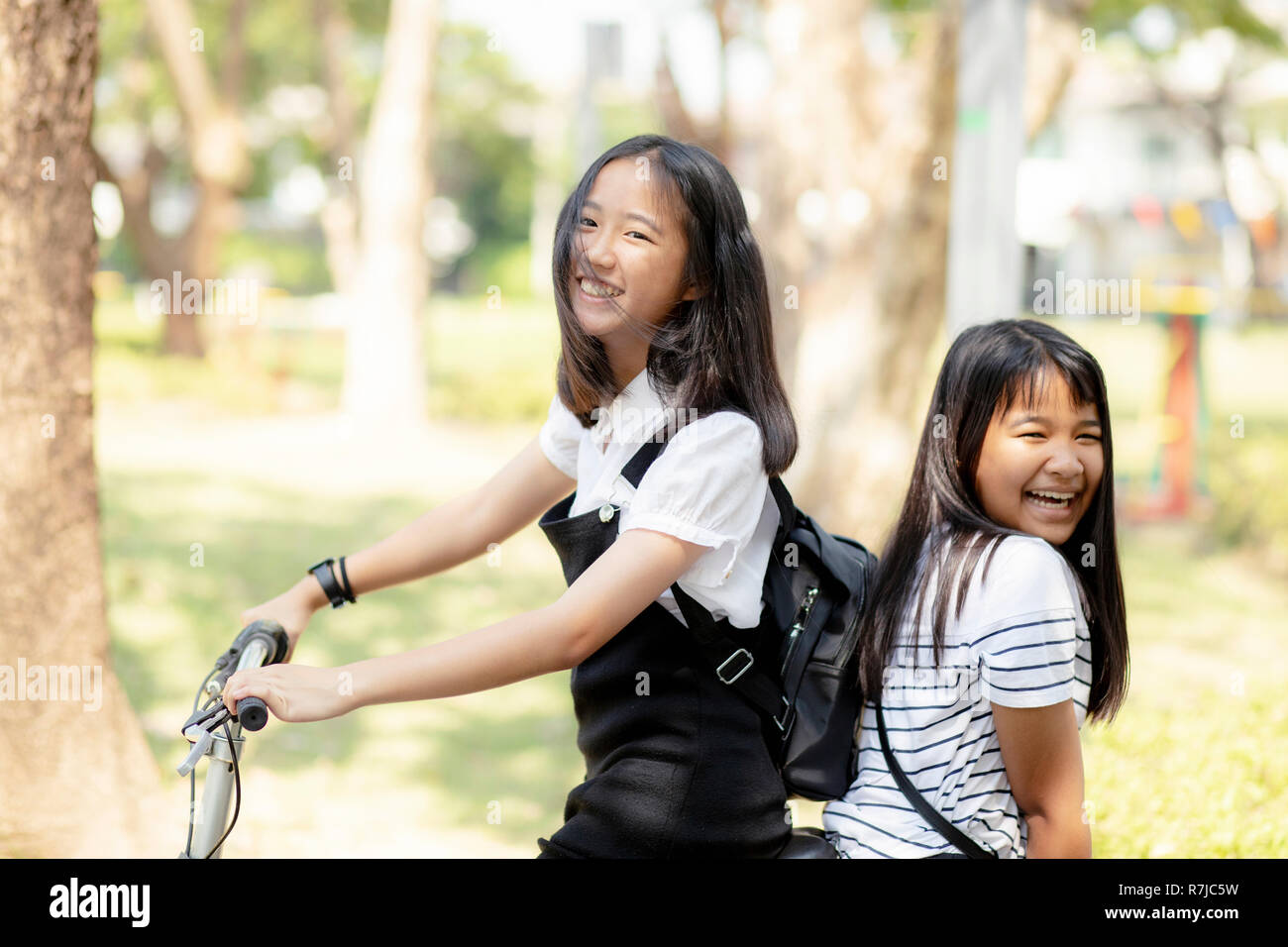 Cheerful asian teenager bonheur émotion riding bicycle in parc public Banque D'Images