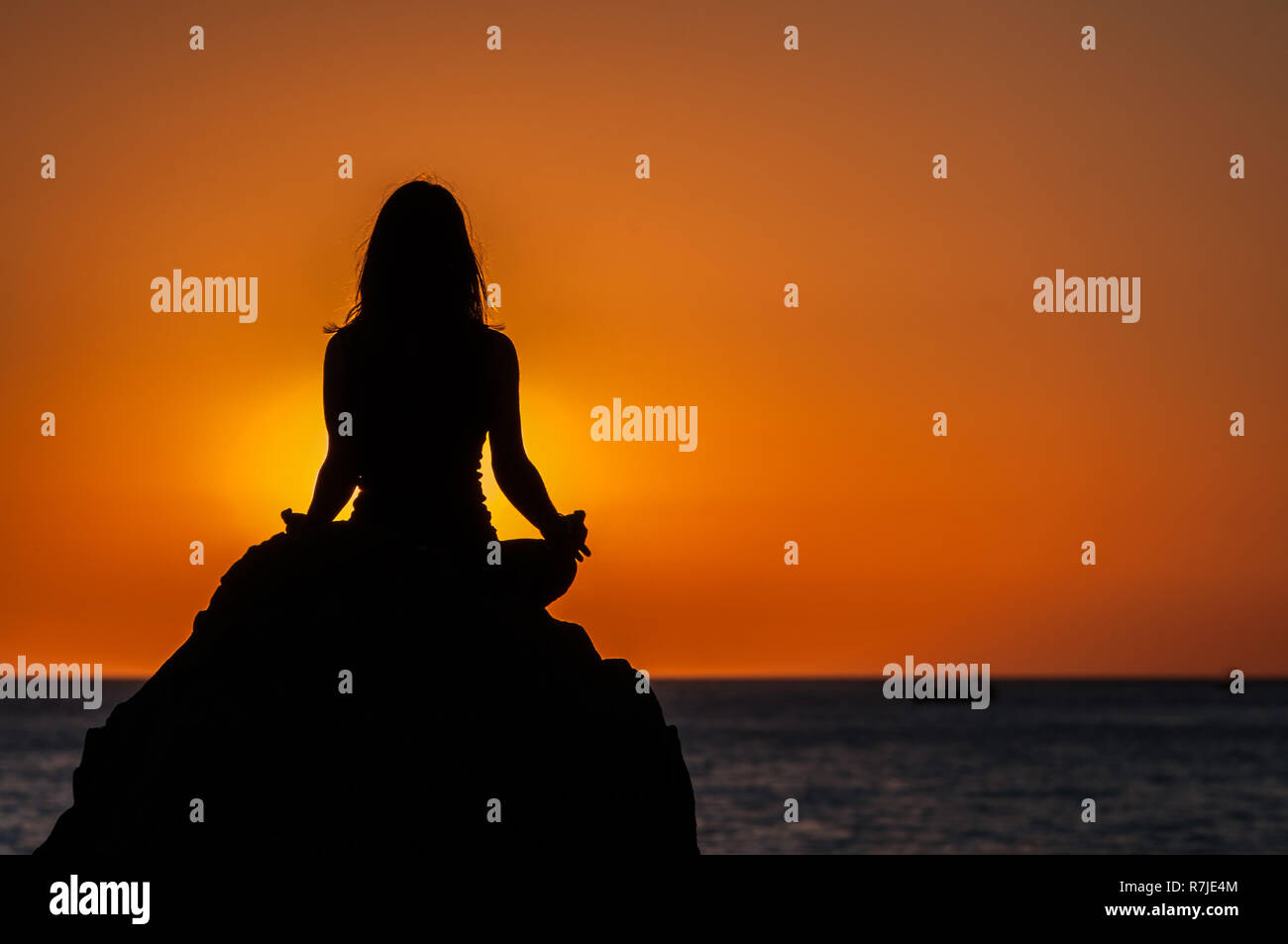 Argelès-sur-Mer (sud-est de la France). Quelqu'un pratique le yoga sur les rochers en face de la plage Racou au lever du soleil. Belle jeune femme avec brown Banque D'Images