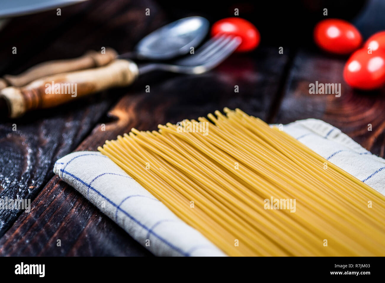 Les pâtes italiennes les spaghettis et les tomates cerises sur la table en bois sombre. Banque D'Images